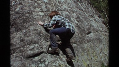 1975: an young lady in jeans attempts to climb a sheer rock face AGATE SPRINGS