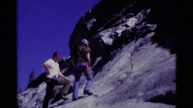 1975: two men climb the steep face of a mountain using a single safety rope