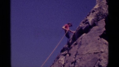 1975: a man in a red t-shirt is rappelling down the side of a mountain MINARET