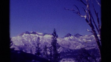 1975: Dark and Pointed Twin Peaks Rise Above Snow and Trees in Minaret Wilderness, California