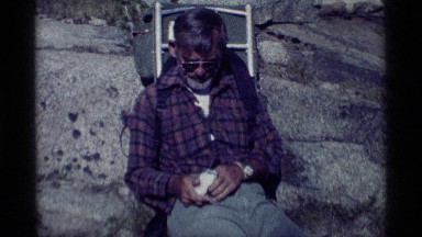 1975: an elderly man is sitting on the ground while he has a smoking pipe