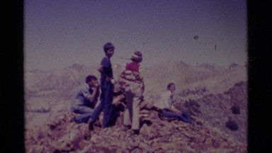 1975: people on a ridge with a stack of rocks and a man pointing out