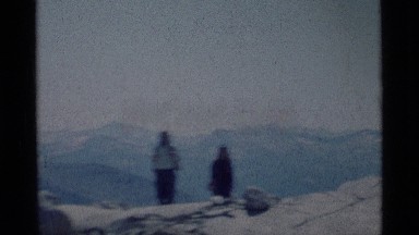 1975: hikers with day packs hiking up a rocky face with valleys and mountains