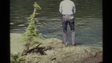 1972: a mature man catches a fish with a rod and reel from the rocky bank