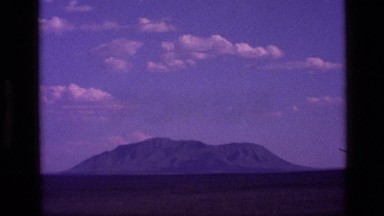 1972: a large mountain ridge amid flatlands under a cloudy blue sky IDAHO