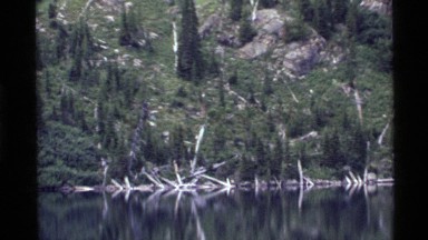 1972: reflective water with a dense forest on its banks HOLLAND LAKE MONTANA