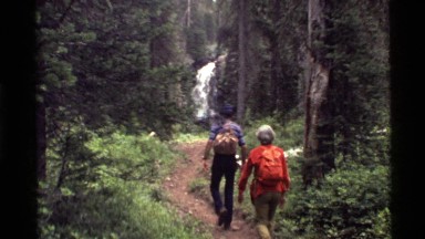 1972: a couple of hikers walk through the forest to a waterfall HOLLAND LAKE
