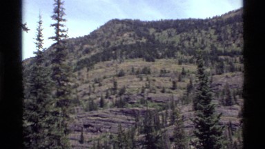 1972: panoramic view of a mountain range with forest HOLLAND LAKE MONTANA
