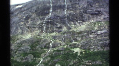 1977: a large rocky mountain with foliage climbing up the base from below ALASKA