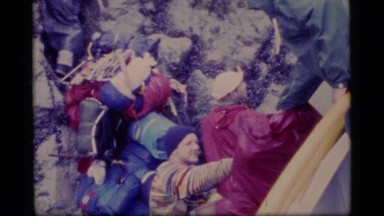 1977: number of people holding their bags and are trying to climb mountain