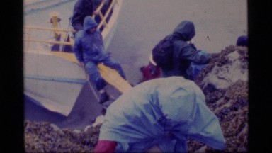 1977: people climbing off a boat over water to get to a very steep cliff GLACIER