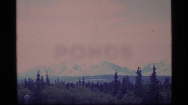 1977: panorama of a mountain valley with trees and jagged peaks in distance