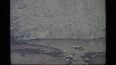 1977: partially frozen lake; lake with boat in it and some ice; someone walking