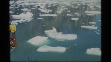 1977: birds fly over a lake while a yellow boat plows through the chunks of ice