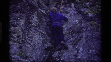 1977: a young boy in hiking shoes moving on his first climbing lesson on a