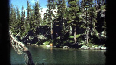 1977: a river flowing calmly in the middle of mountain area with people around