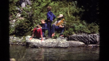 1977: man and his children gathered near the river bank and enjoying