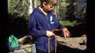 1977: a boy outside in a sweatshirt tying a rope around his waist