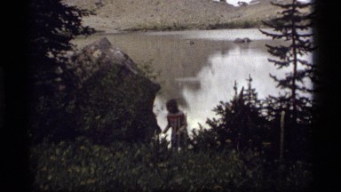 1977: woman walking up from mountain lake with a peak and snow SAPPHIRE LAKE