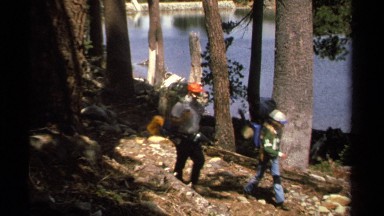 1978: four backpackers walking on a trail in a forest by a lake LAKE TAHOE