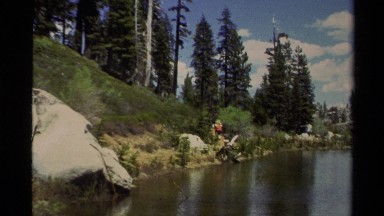 1978: backpackers hiking a trail in the woods near a lake; two backpackers