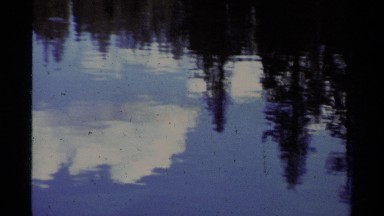 1978: reflection of clouds and trees in body of water with snow on shoreline