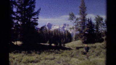 1979: a woman walking through a beautiful meadow set against snow