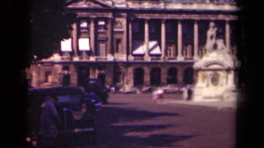 1939: black and white video of people walking and driving near a long bridge.