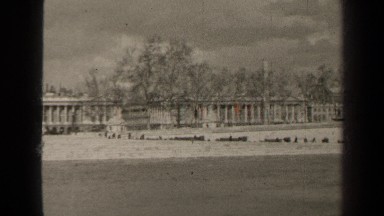 1947: river flows in front of low and wide buildings with row of columns