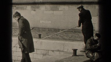 1947: two men fish with long poles off a stone wall on a windy day PARIS FRANCE