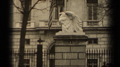 1947: in front of government building that has a big eagle statue beside a tree