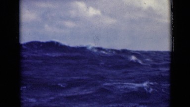 1947: Large White-Crested Waves in Ocean Crash and Swirl Against Cloudy Sky