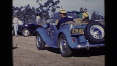 1952: woman checks clipboard with information from driver of blue roadster