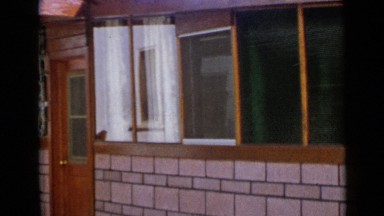 1953: front of house has door, large windows, bricks, and covered entry