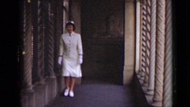1947: woman in white military uniform walks through passageway of columns