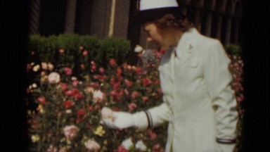 1947: female sailor in white uniform looking at pink and red roses NEW YORK