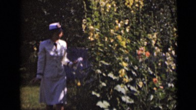 1947: very beautiful women in white dress checking green plantations