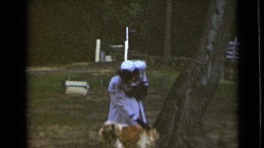 1947: woman, dressed in uniform, standing in yard petting dog NEW YORK