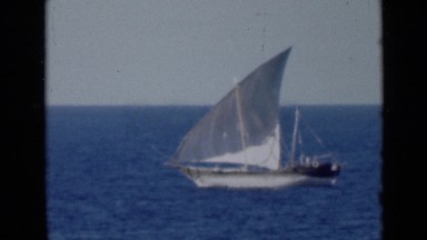 1947: sailboat travels along deep ocean toward giant rock island. PERSIAN GULF