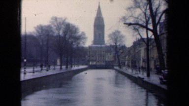 1946: treelined water canal with building and tower at one end and bridge