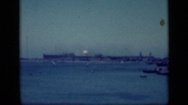 1946: shoreline with long low building, white dome tower, and small boats