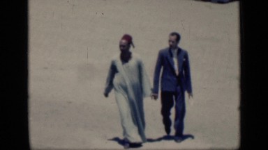 1946: men in different dresses walking down sandy ground EGYPT