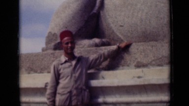 1946: handsome young man with hat standing in front of large stone sculpture