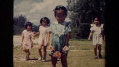 1944: Girl Standing on Grassland with Children in Kauai Hawaii