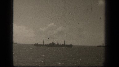 1944: Long and Narrow Battleship Floats on Shining Sea Beneath Puffy Clouds