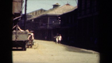 1944: day life in town man riding bicycle and people walking around MANILLA