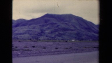 1944: viewing mountain range from dirt road in desert on overcast day.
