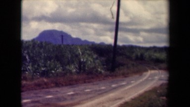 1944: dotted white line crosses paler curved parallel lines on remote road KAUAI