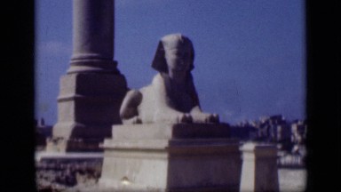 1946: Egyptian Man Standing Alongside Ancient Statue and Posing in Egypt