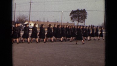 1947: women in uniform marching in formation through parking lot. NEW YORK